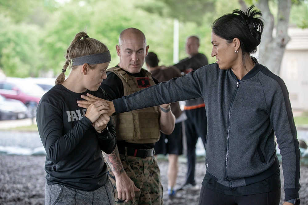 Two educators are instructed by a Marine in martial arts.